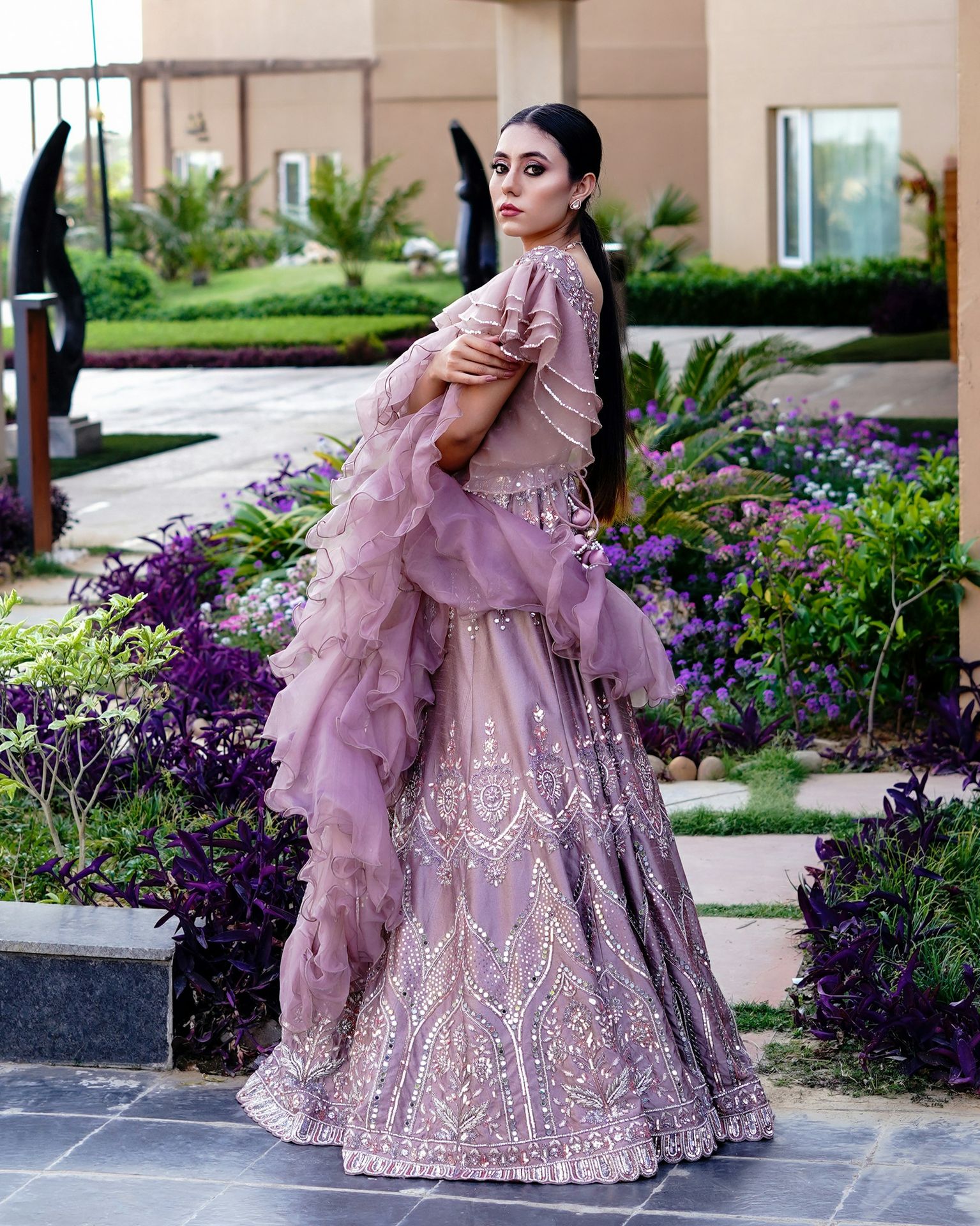 a woman in a purple dress standing in a garden